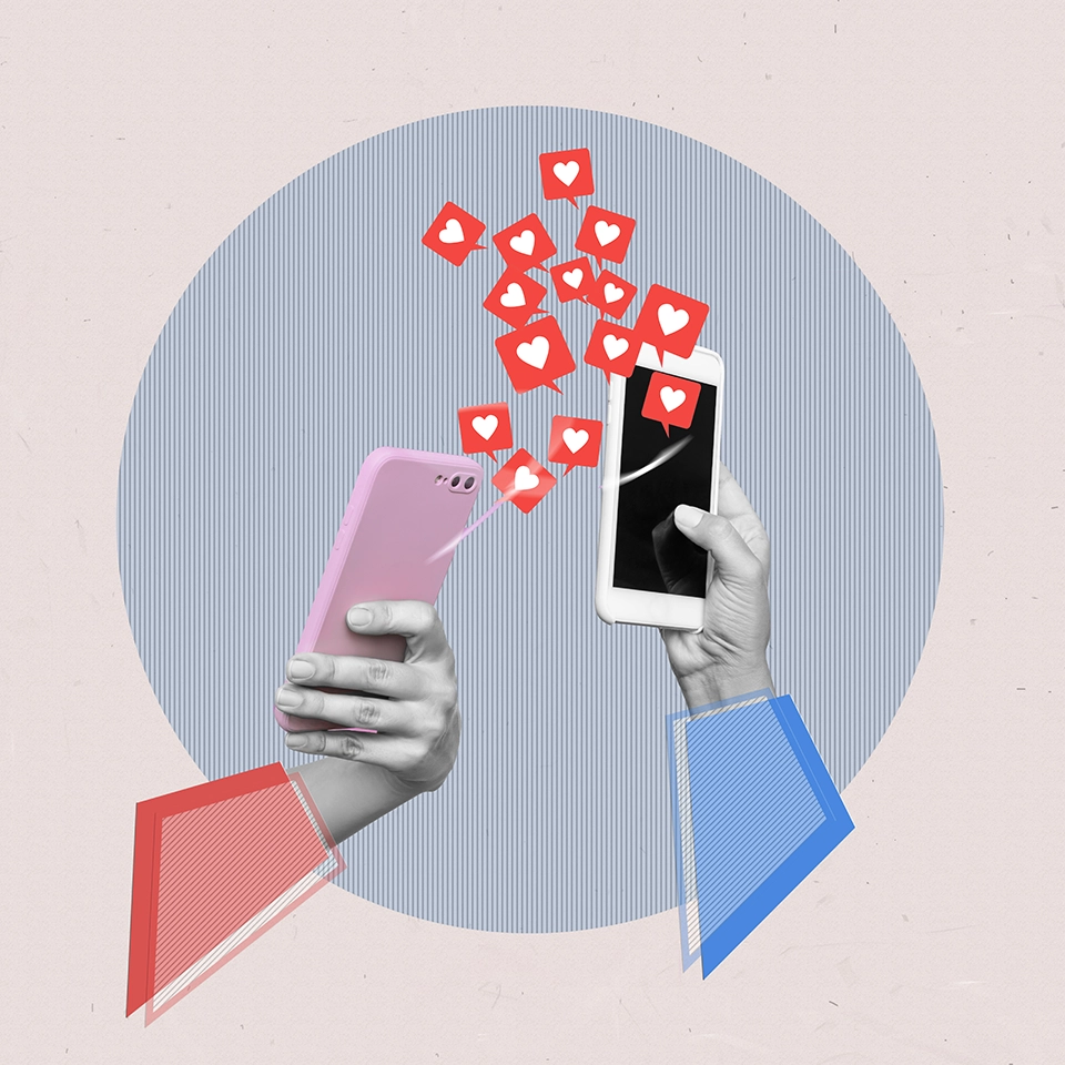 Dos manos sostienen teléfonos móviles con iconos de corazones flotando entre ellos, simbolizando la interacción y el crecimiento en redes sociales en Zaragoza.